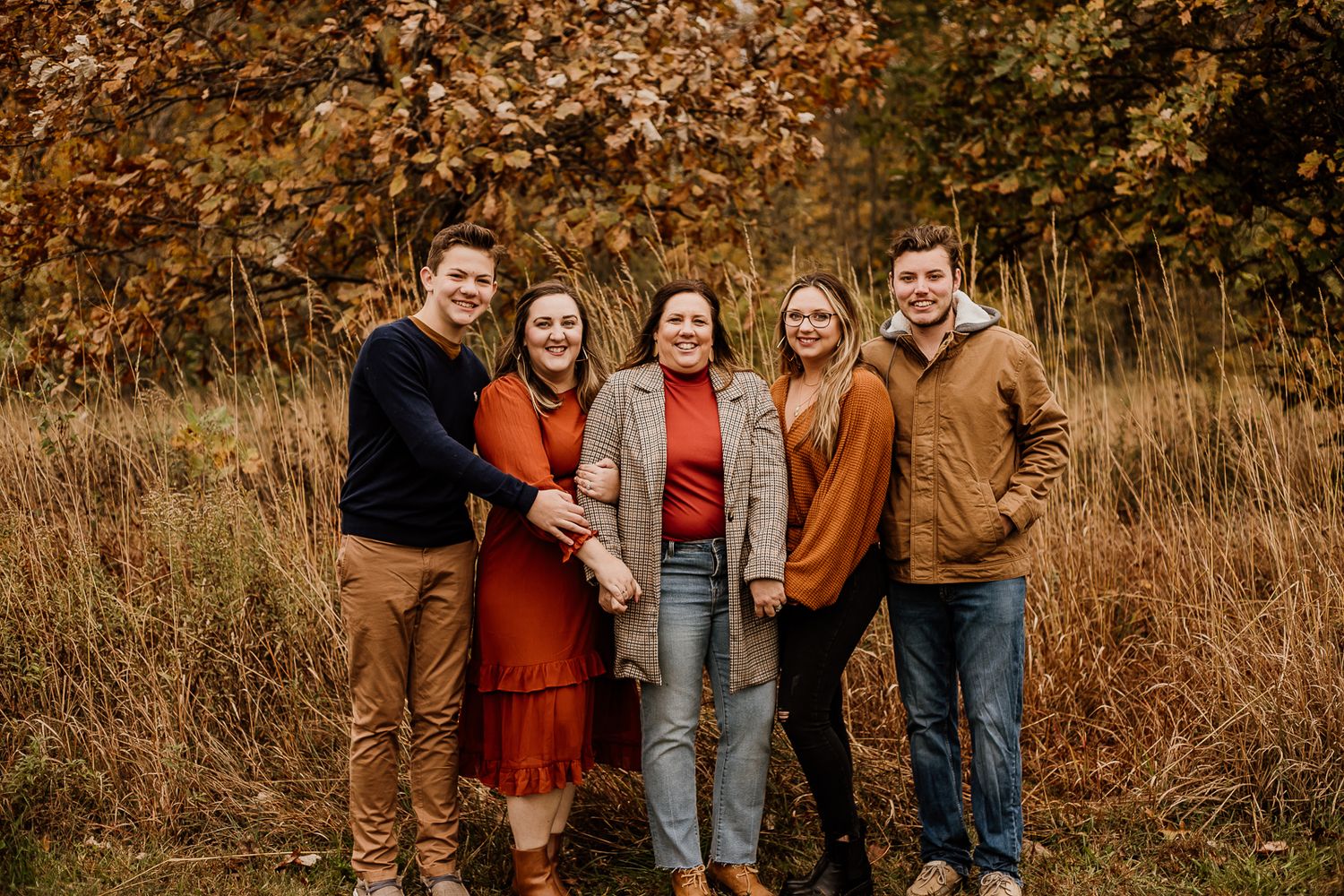 Family group portrait in warm earth tones against golden fall landscape.