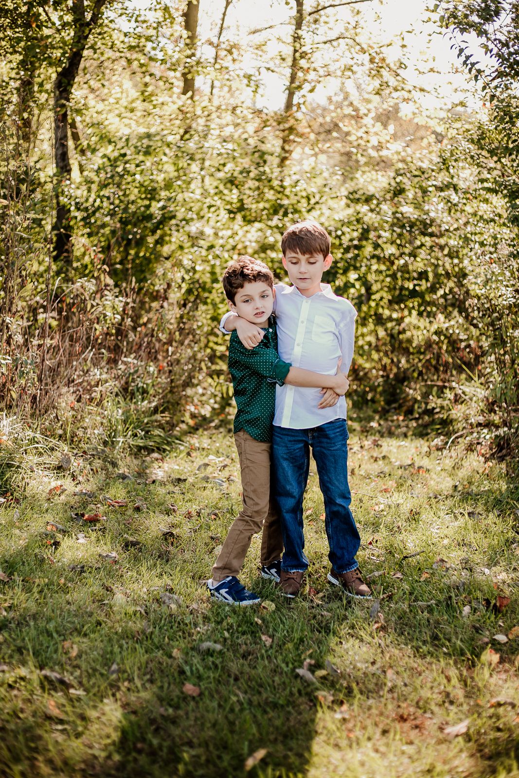 Children playing together in sunlit wooded area during golden hour.