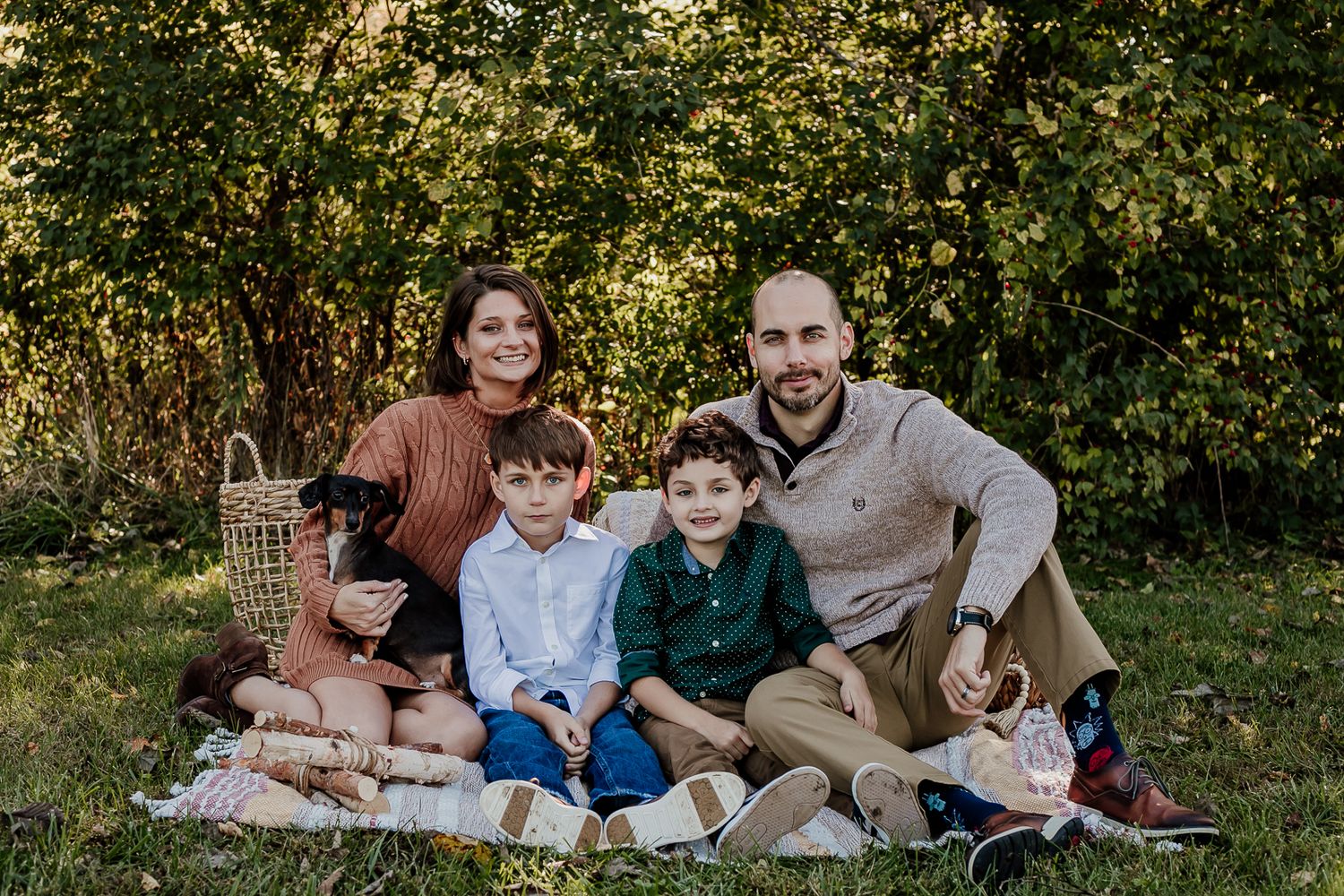 Family lounging on blanket for casual outdoor photo session.