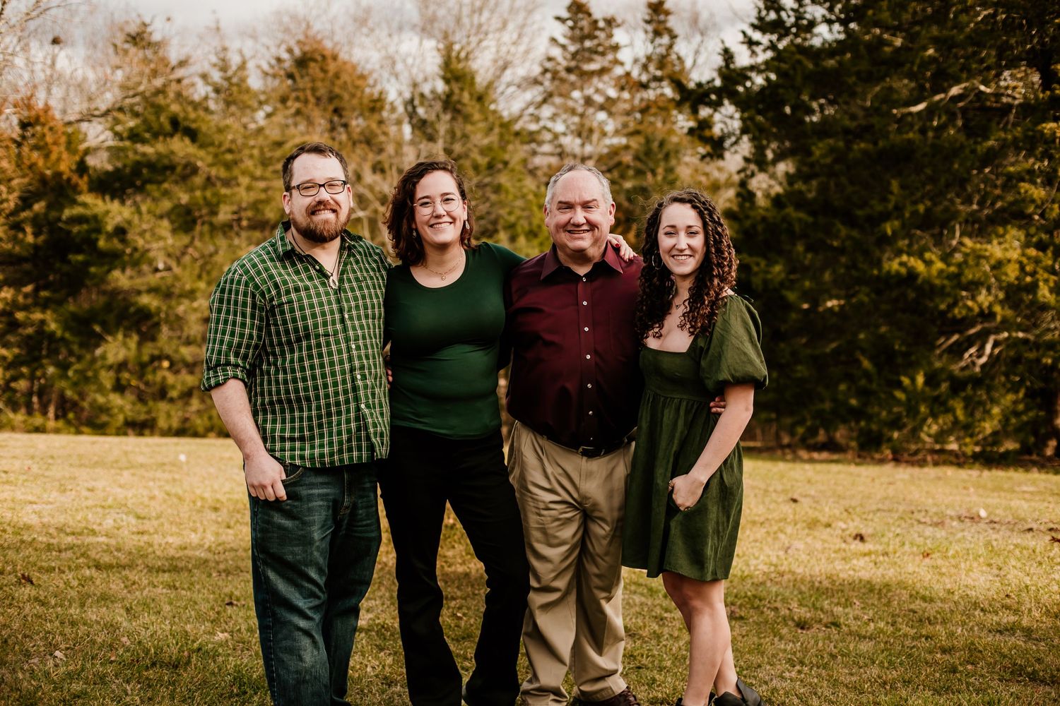 Group photo of family members wearing coordinated green and burgundy clothing outdoors.