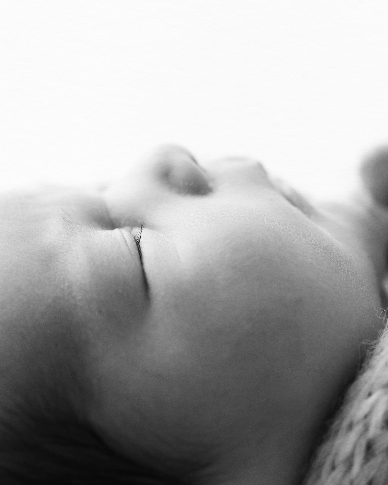 Artistic black and white macro shot of sleeping baby's profile.