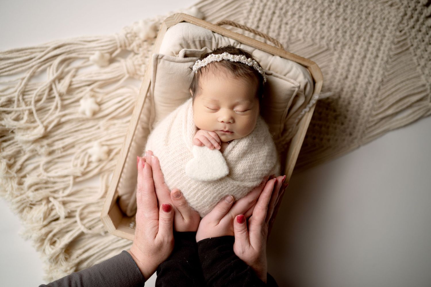Newborn baby nestled in cream macrame blanket with soft neutral tones.