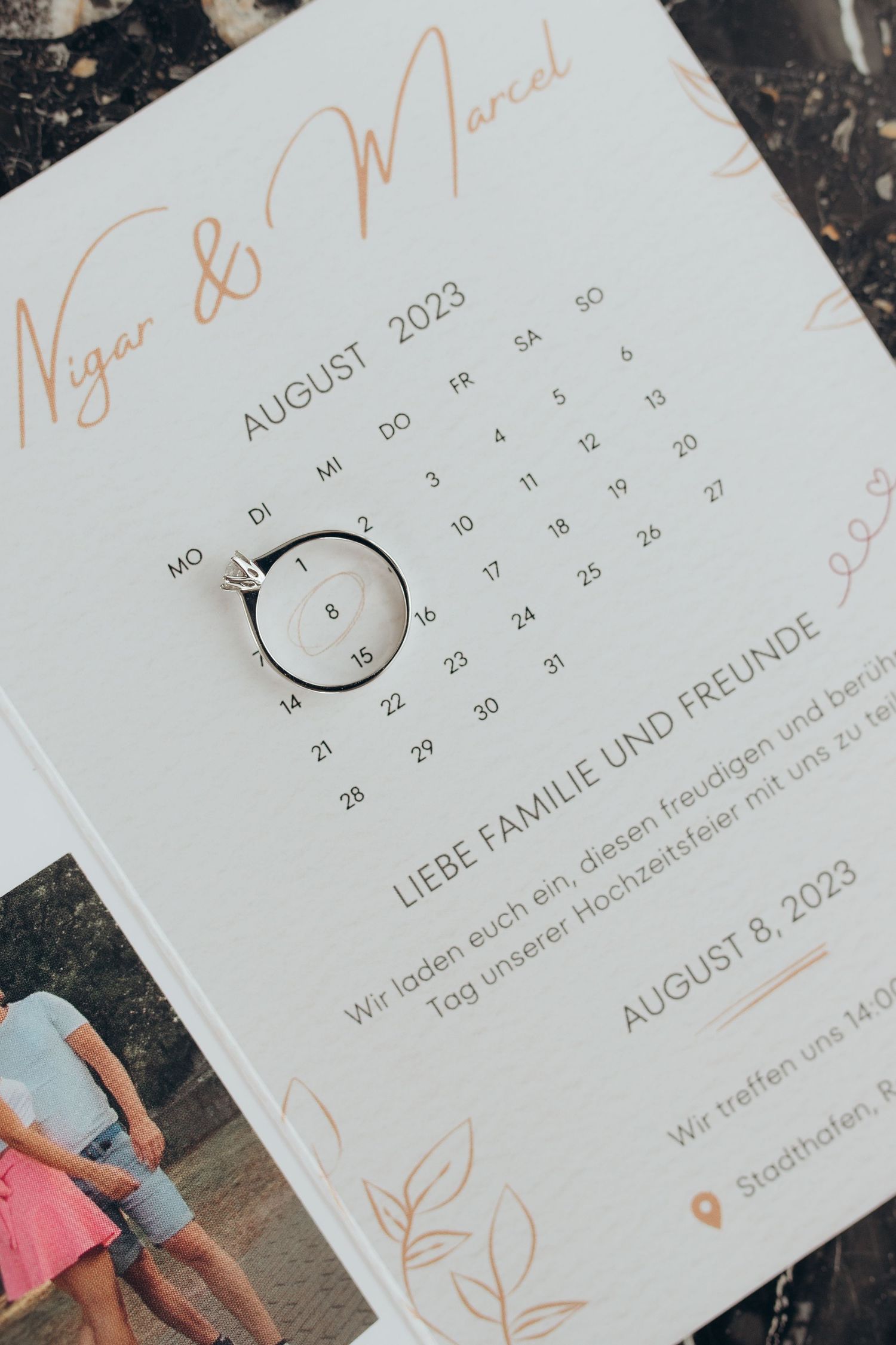 Wedding invitation calendar showing August 2023 with elegant text in German and rose gold design elements.