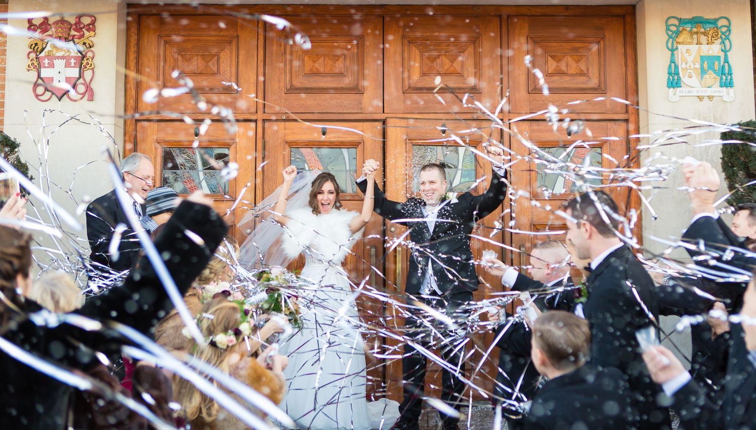 Wedding celebration captured with streamers flying in front of ornate wooden doors.
