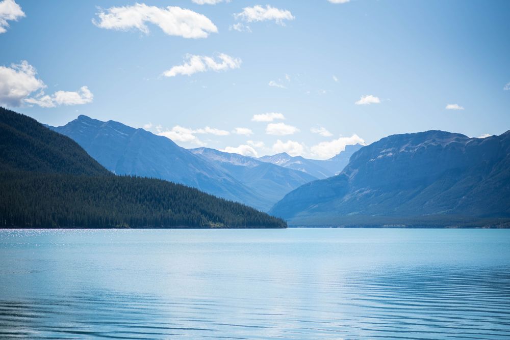 Serene mountain lake landscape with blue waters and distant peaks under summer sky.