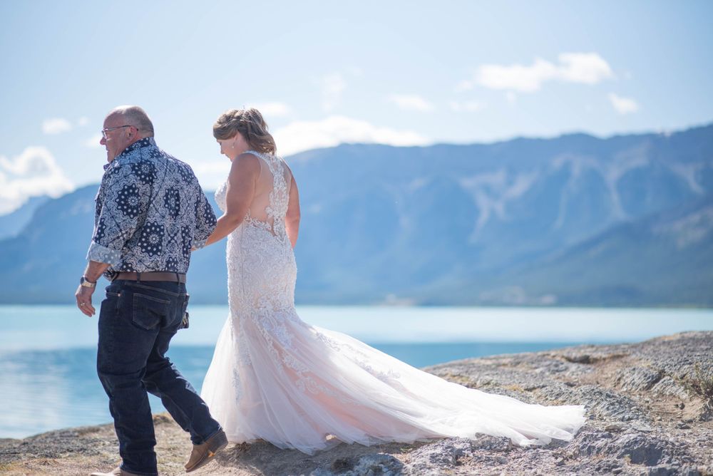 A couple walks along a scenic mountain ridge with turquoise lake views.