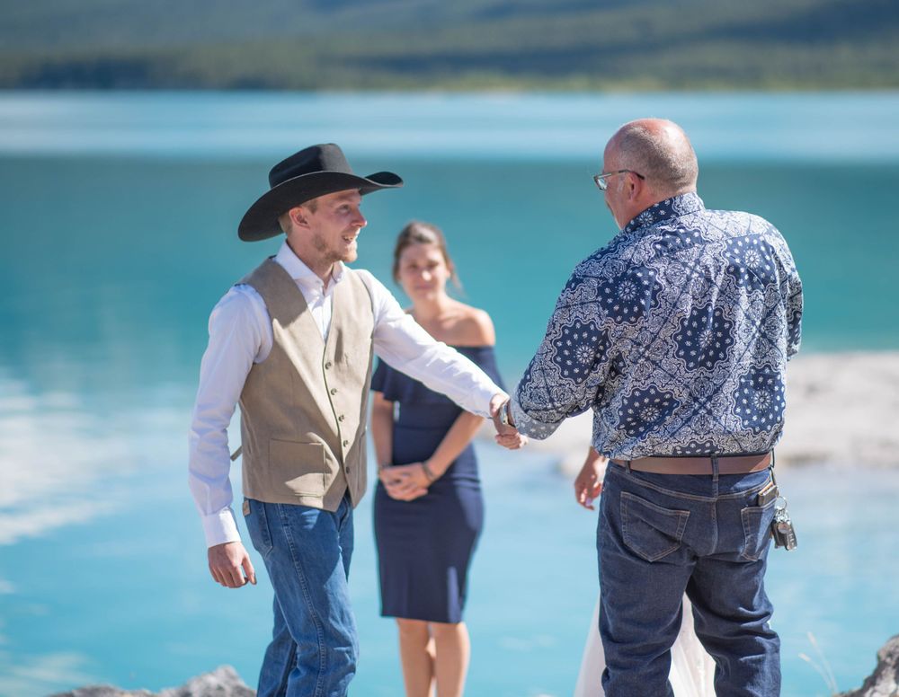A scenic mountain wedding ceremony with turquoise lake waters in the background.