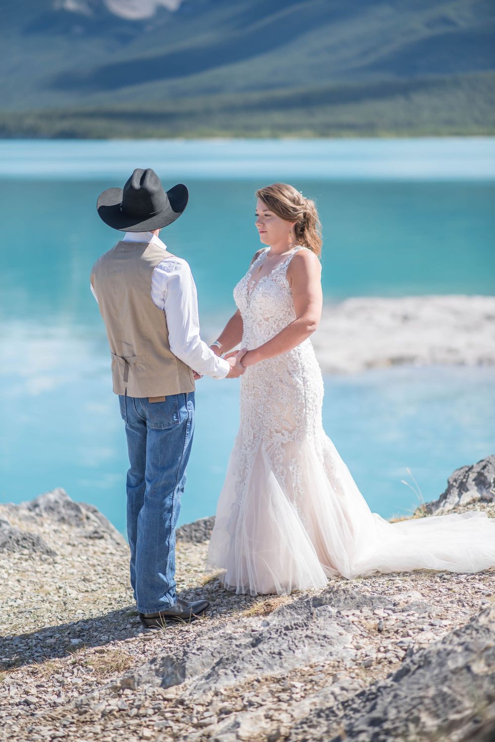 A wedding ceremony unfolds on a rocky outcrop overlooking turquoise mountain waters.