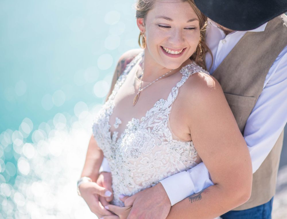 Sunlit embrace with sparkling water backdrop.