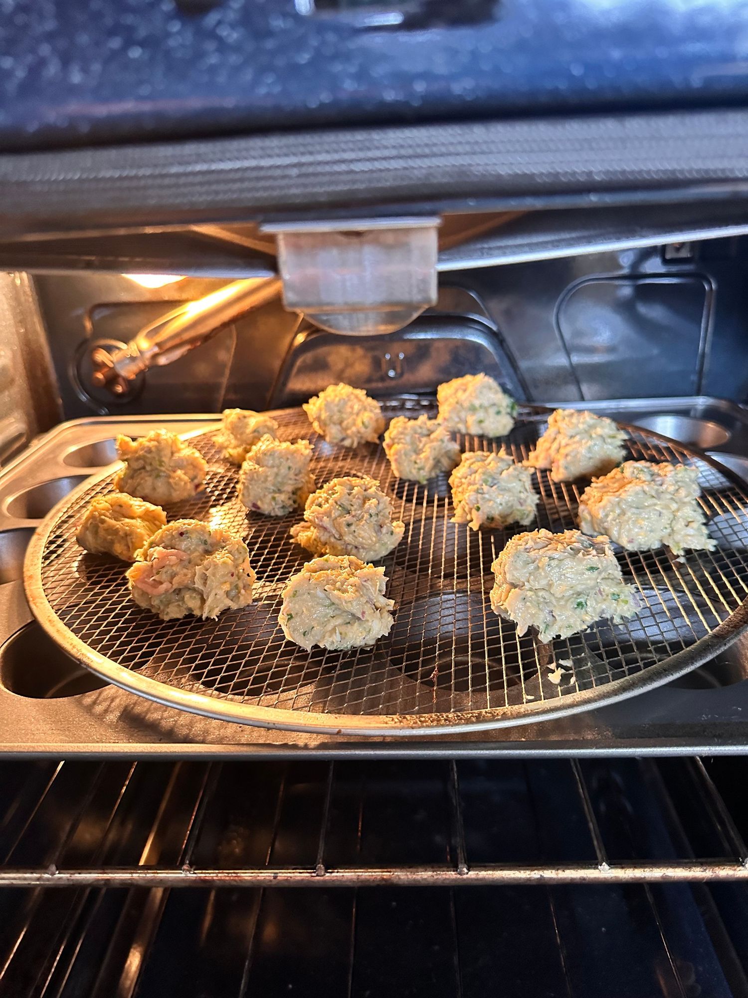 Homemade meatballs cooking on a round wire rack in the oven.