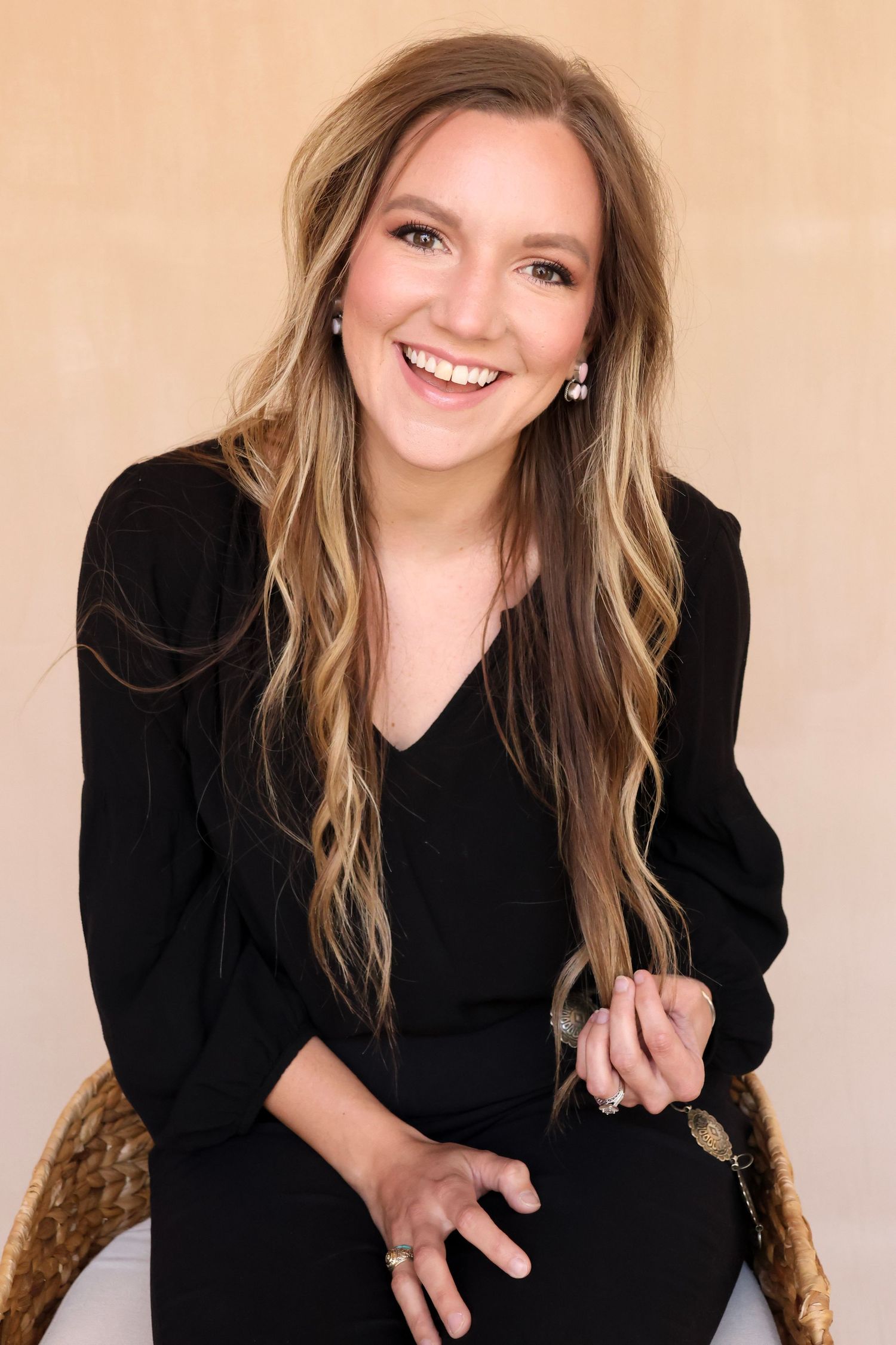 Portrait session against beige backdrop wearing black attire.