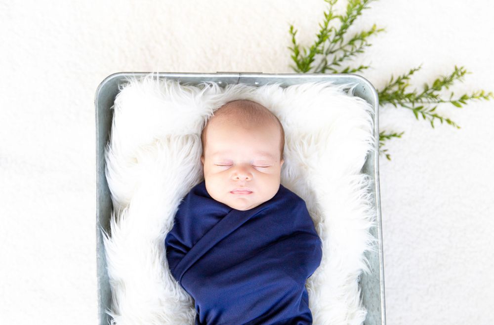A peaceful newborn baby sleeping soundly, wrapped in a soft blanket, with delicate features in serene repose, showcasing