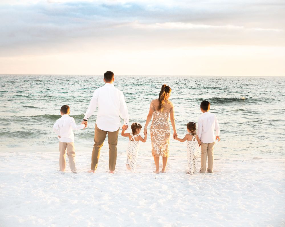 A loving family portrait featuring parents and children, posing together with genuine smiles on a beautiful beach