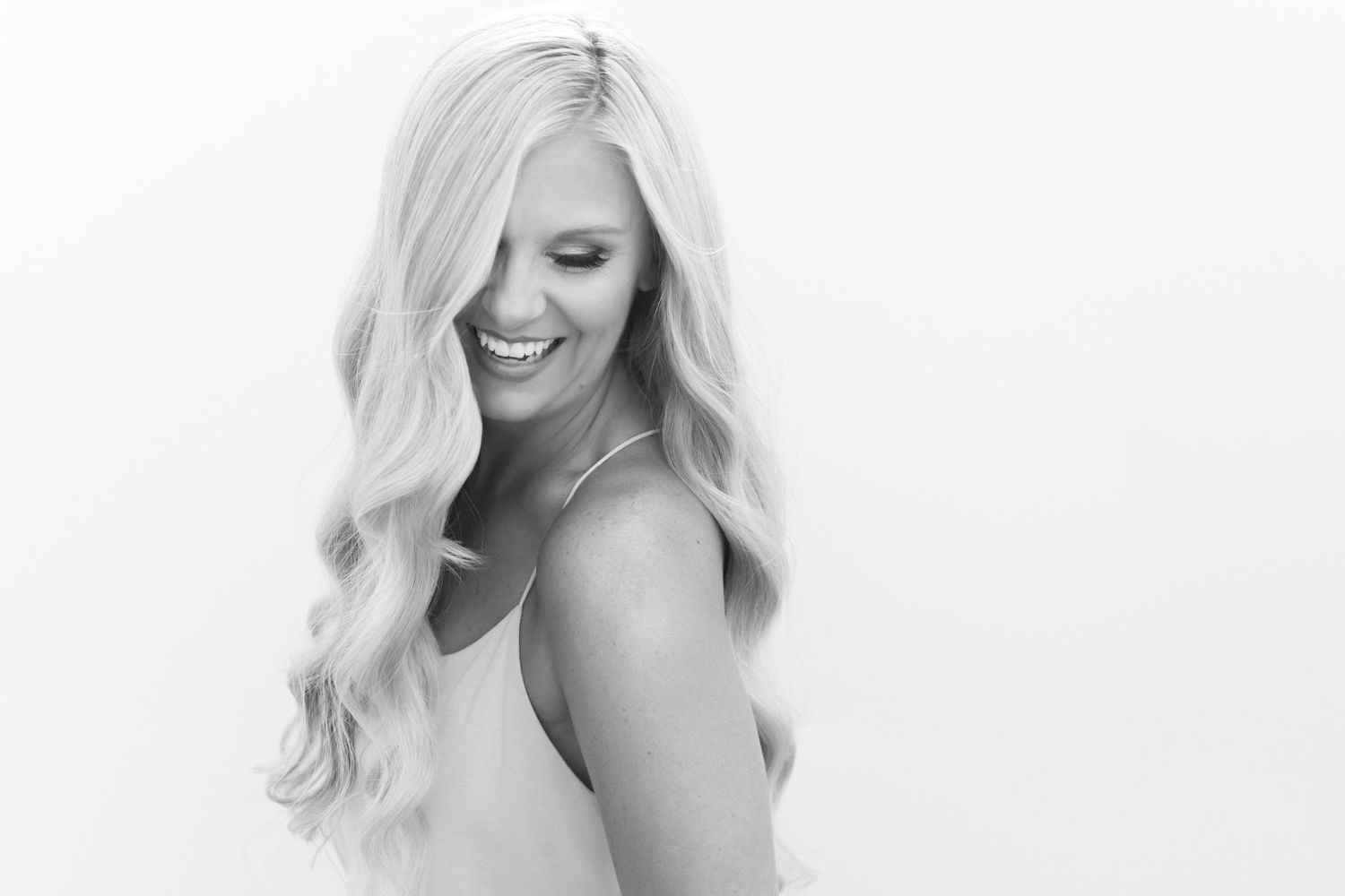 Black and white portrait of photographer with wavy blonde hair smiling.