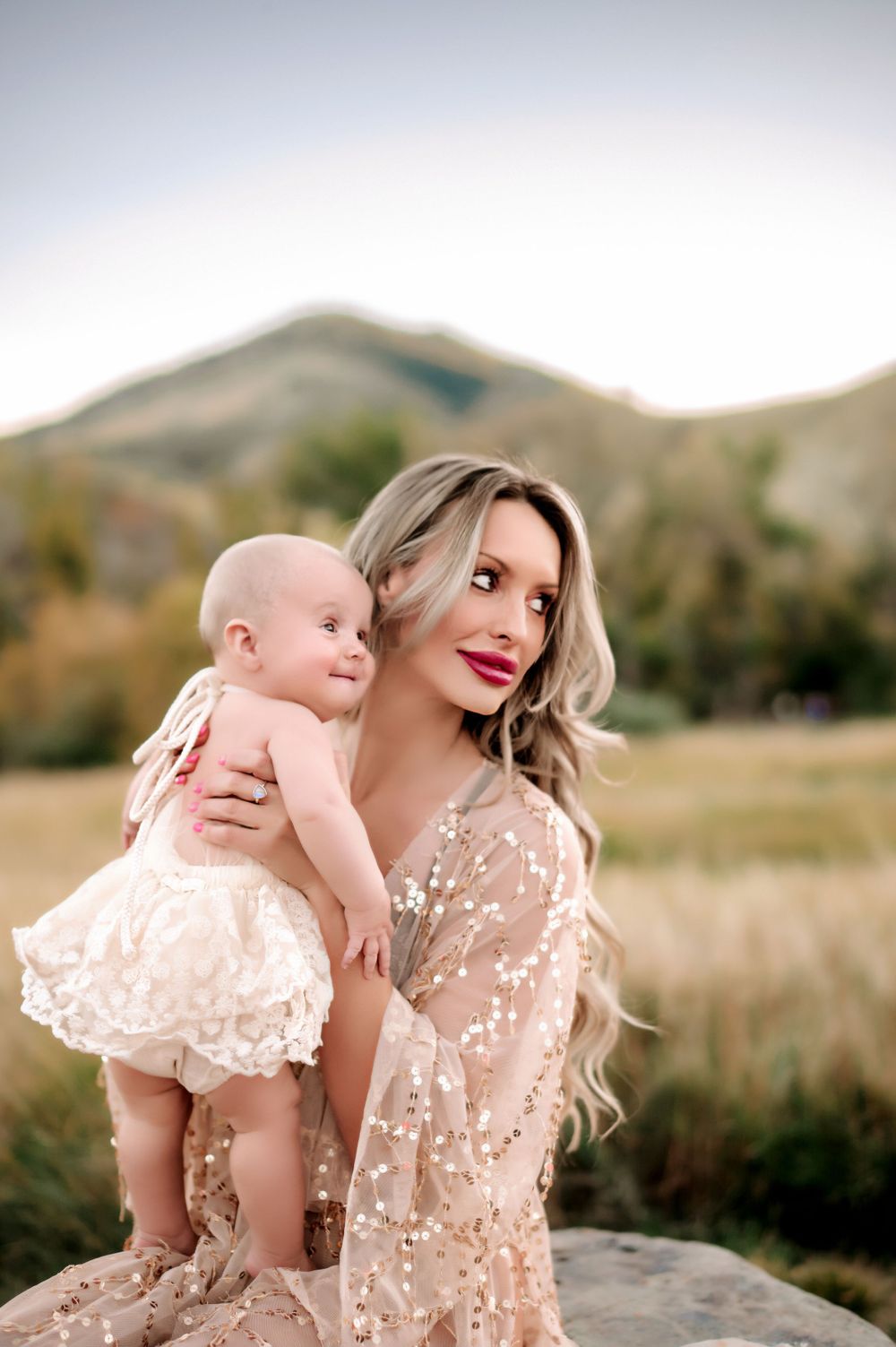 A tender moment captured between mother and baby against a mountainous landscape.
