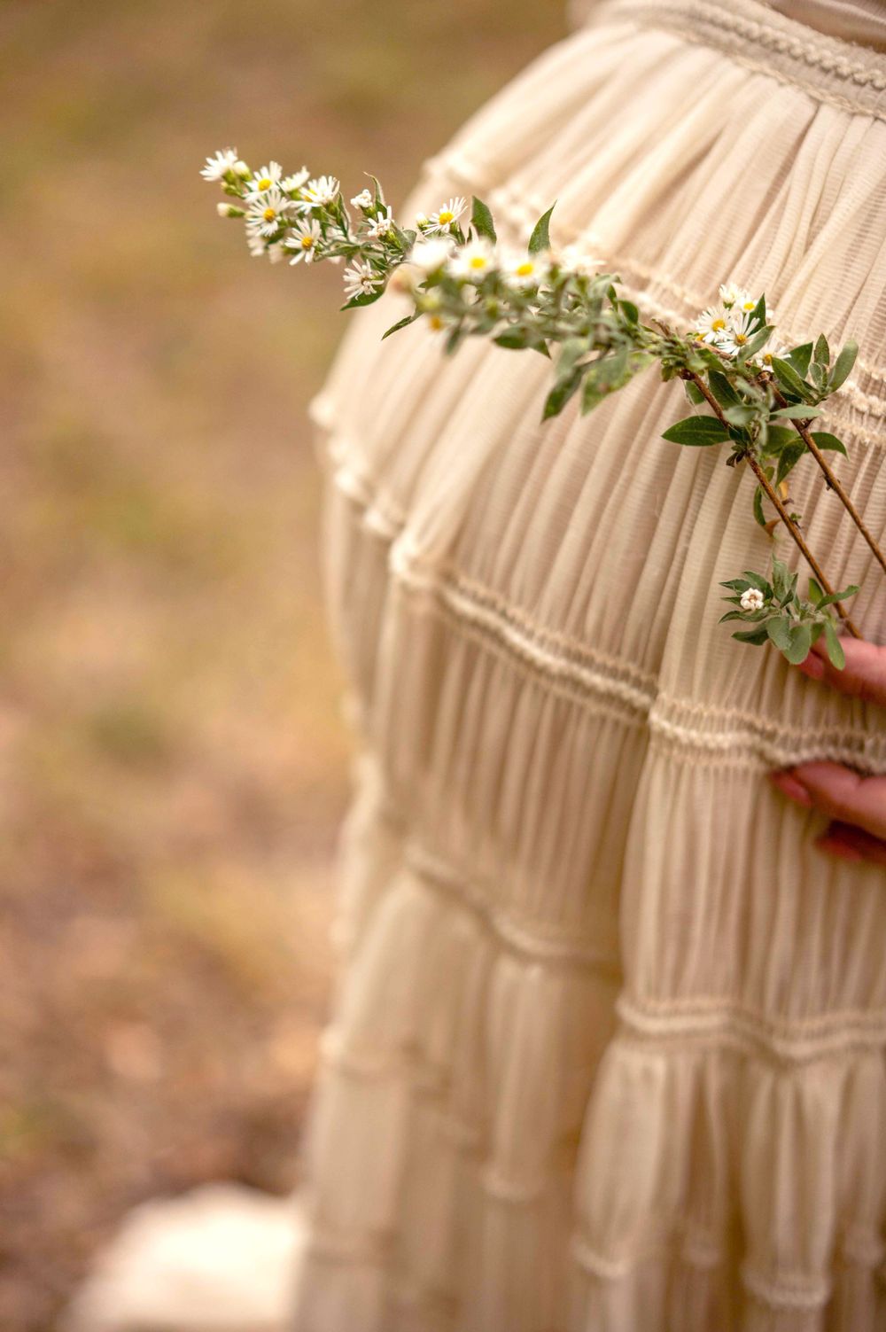 Close-up of delicate white flowers on cream-colored ruffled dress fabric.