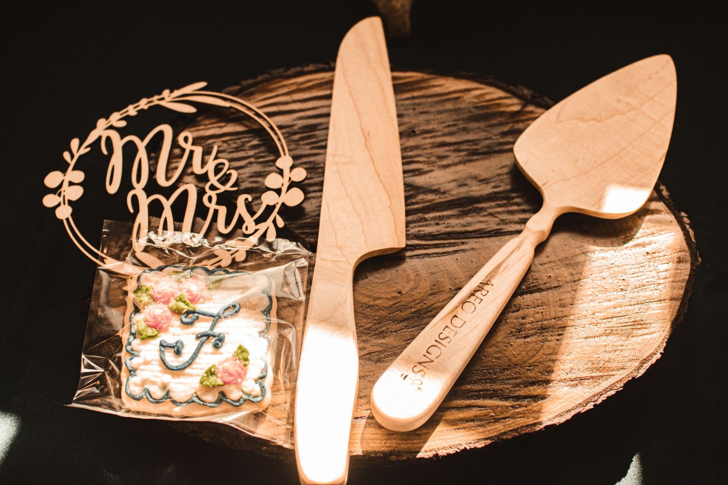 Wedding cake cutting set and 'Mr & Mrs' topper on a rustic wooden board.
