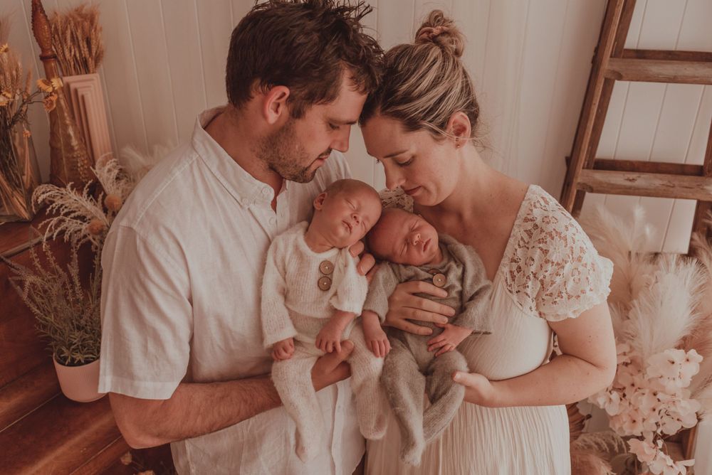 Family portrait with twins and parents in soft neutral tones with dried floral accents.