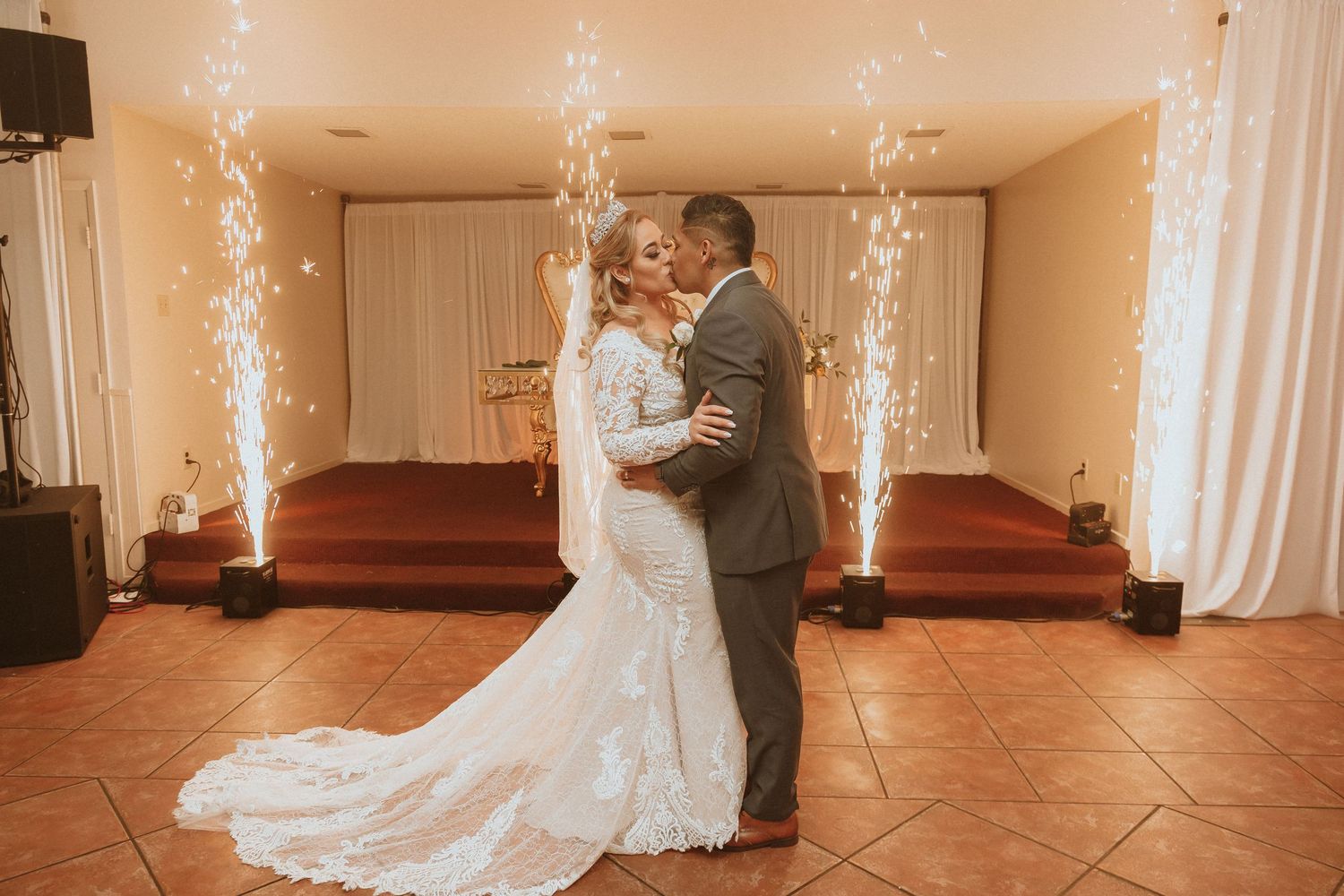 A wedding couple dances in an indoor venue with sparkler fountains creating a magical atmosphere.