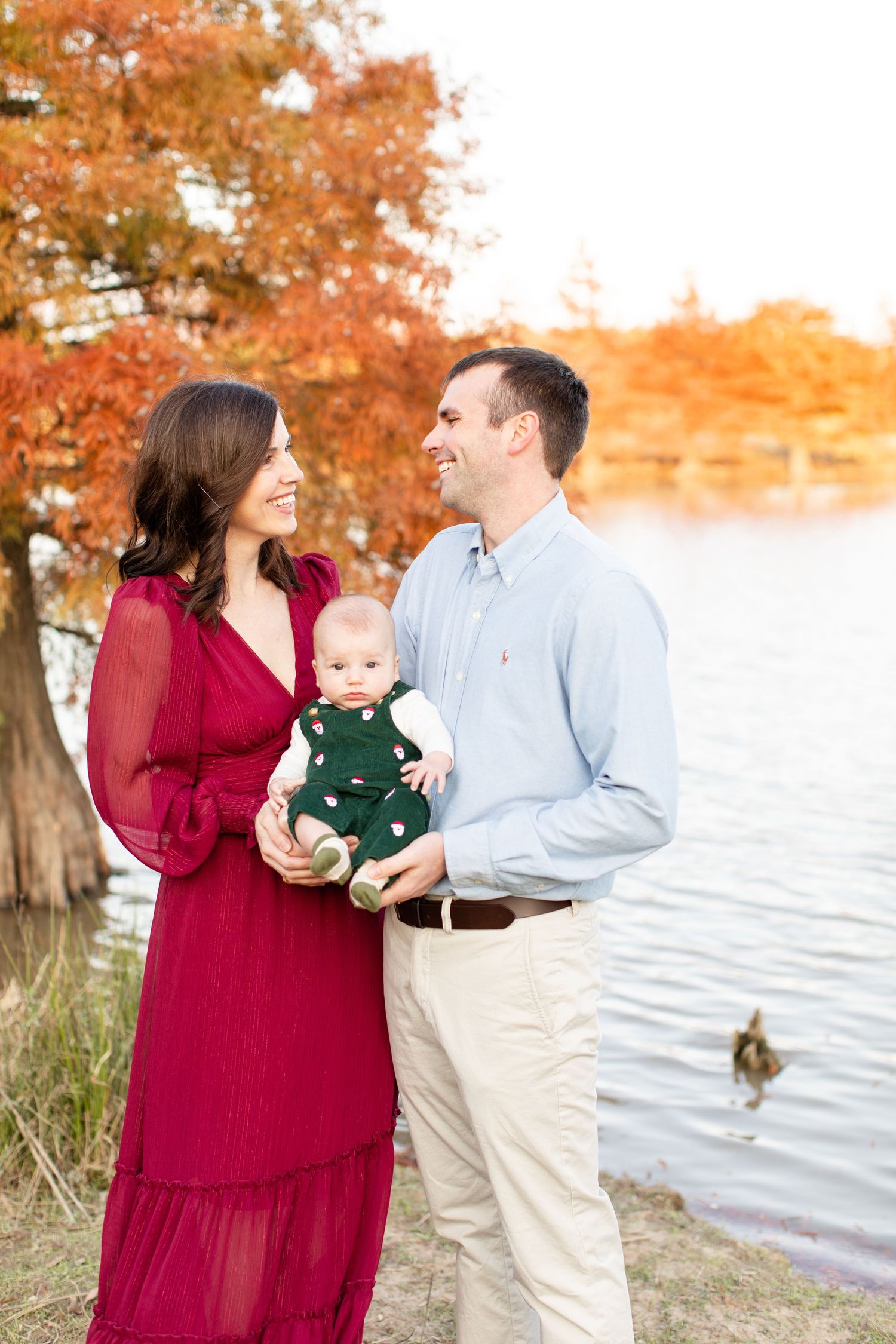 Romantic family moment by lakeside with fall foliage and swimming duck in background.