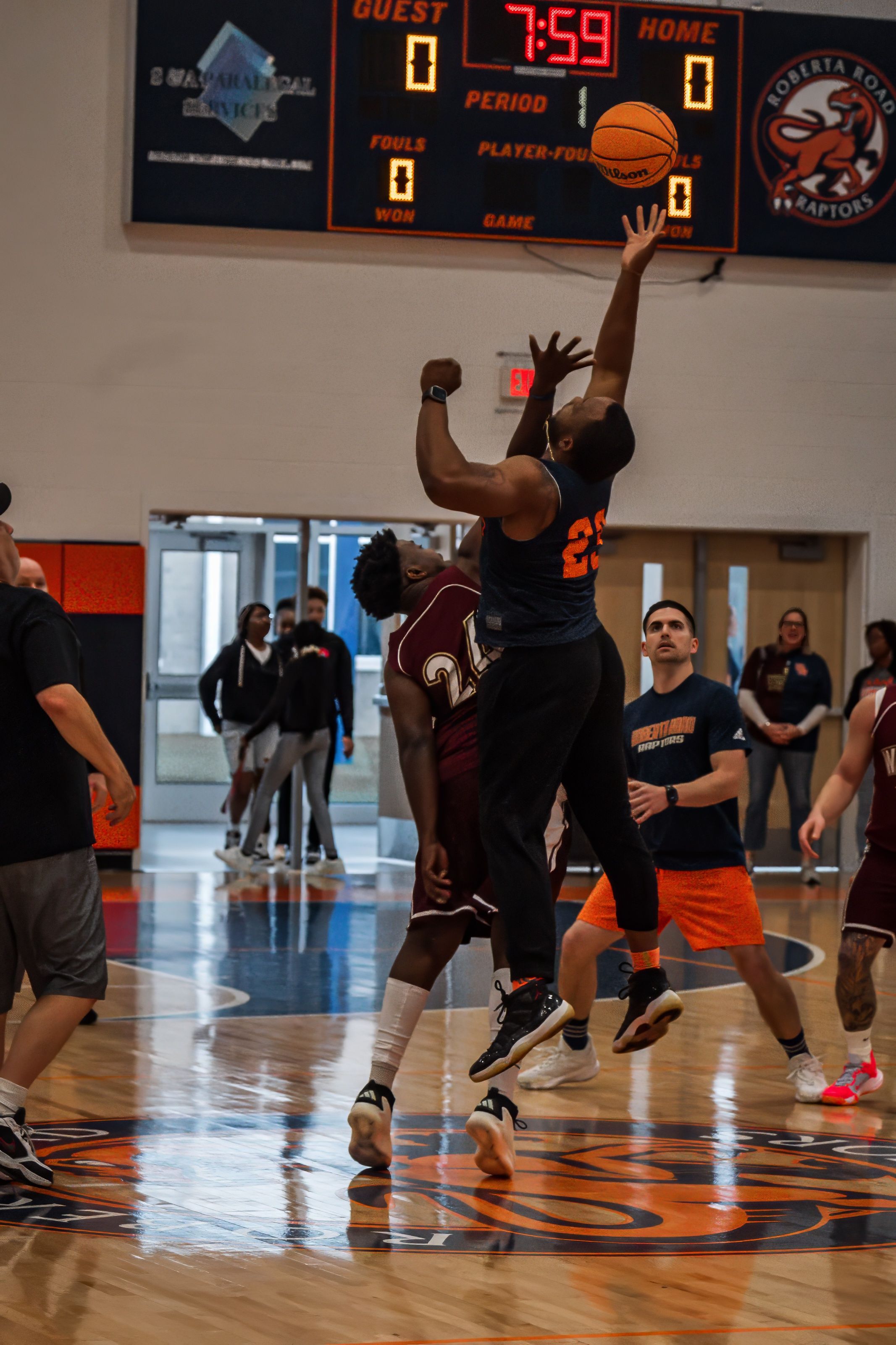 Basketball player jumps high for a layup during an indoor game.