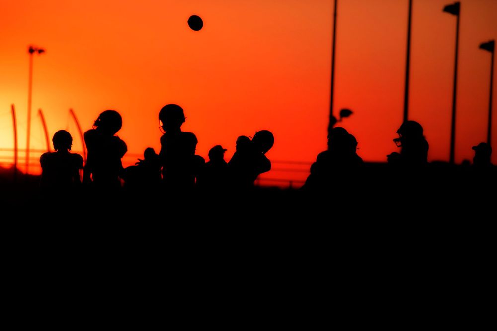 Silhouettes of athletes practicing against vibrant orange sunset sky.