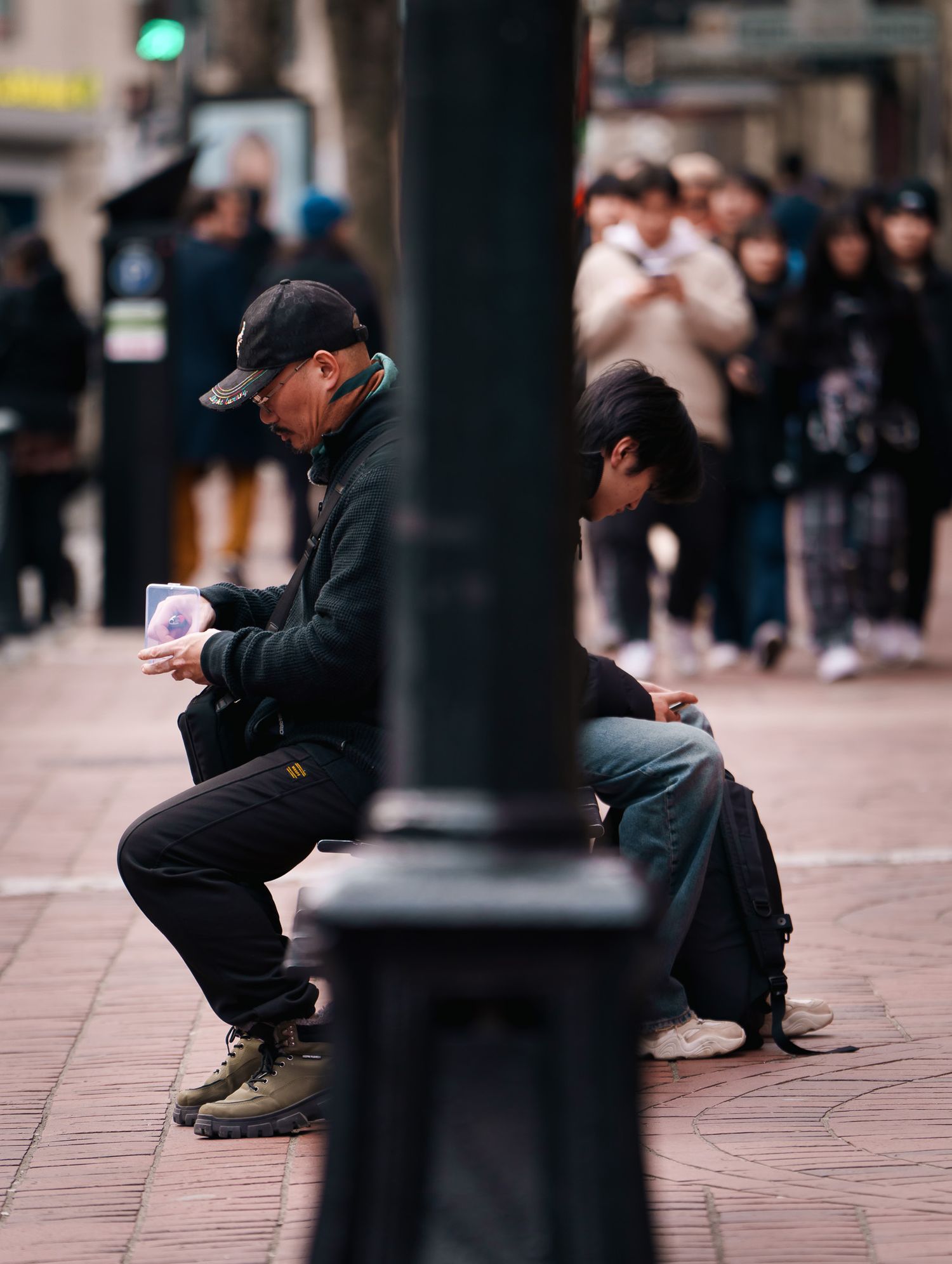 A older man on the left and a younger man on the right with a street light dividing the two, street photography.