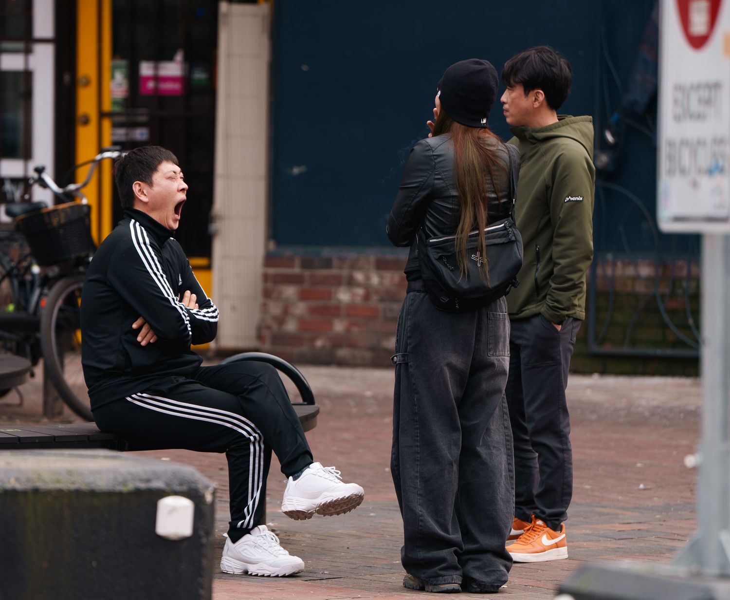 A man yawning as a woman and a man stood there , street photography