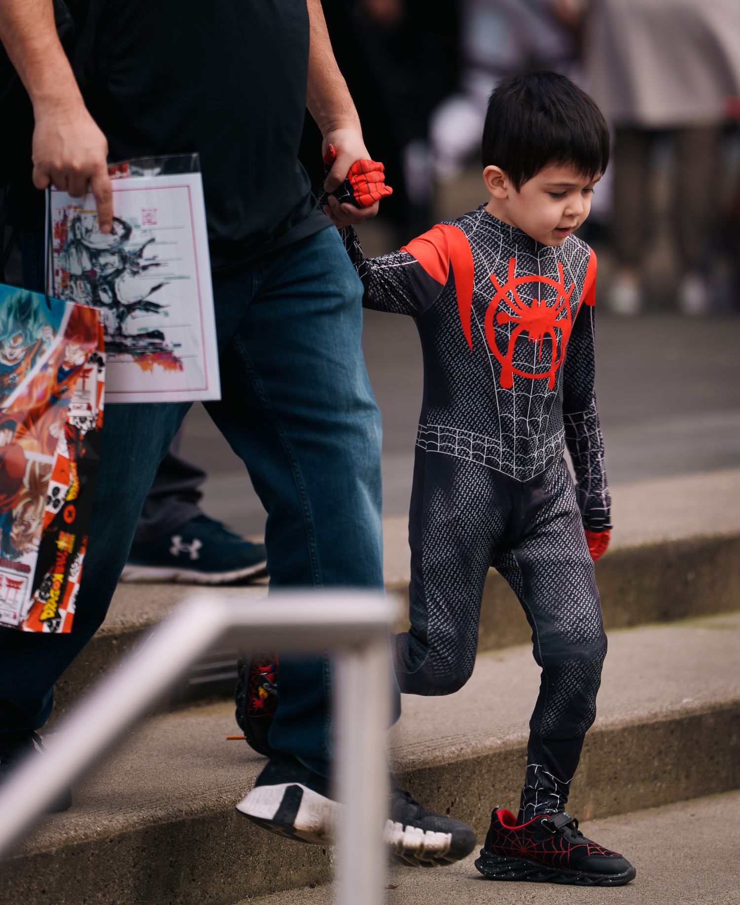 A young boy dressed as spider-man walking down the stairs, street photography.