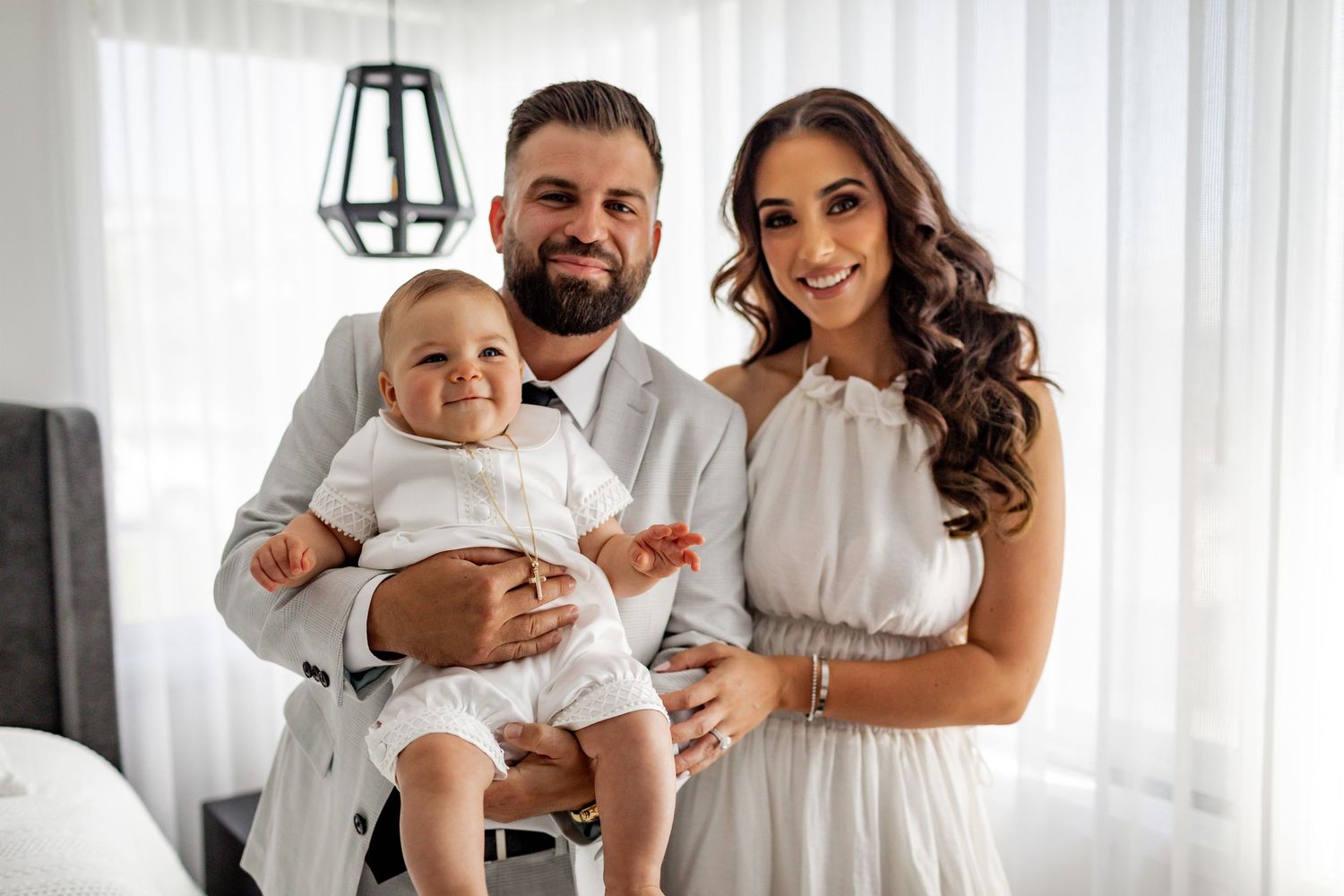 Family wearing white outfits in bright modern living room.