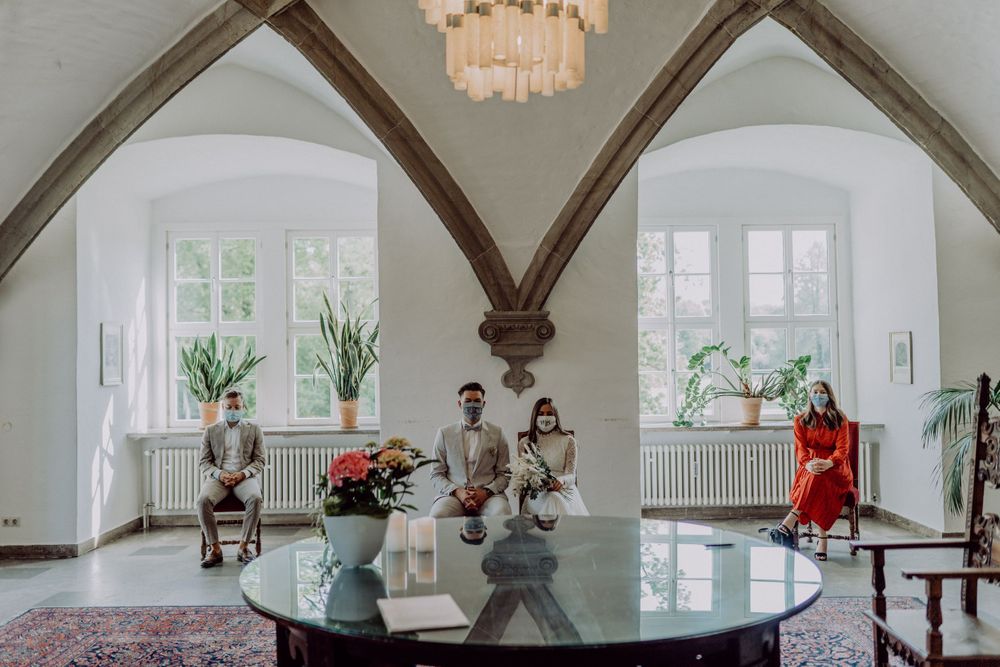 Interior ceremony space with arched ceiling, glass table, and red velvet chairs.