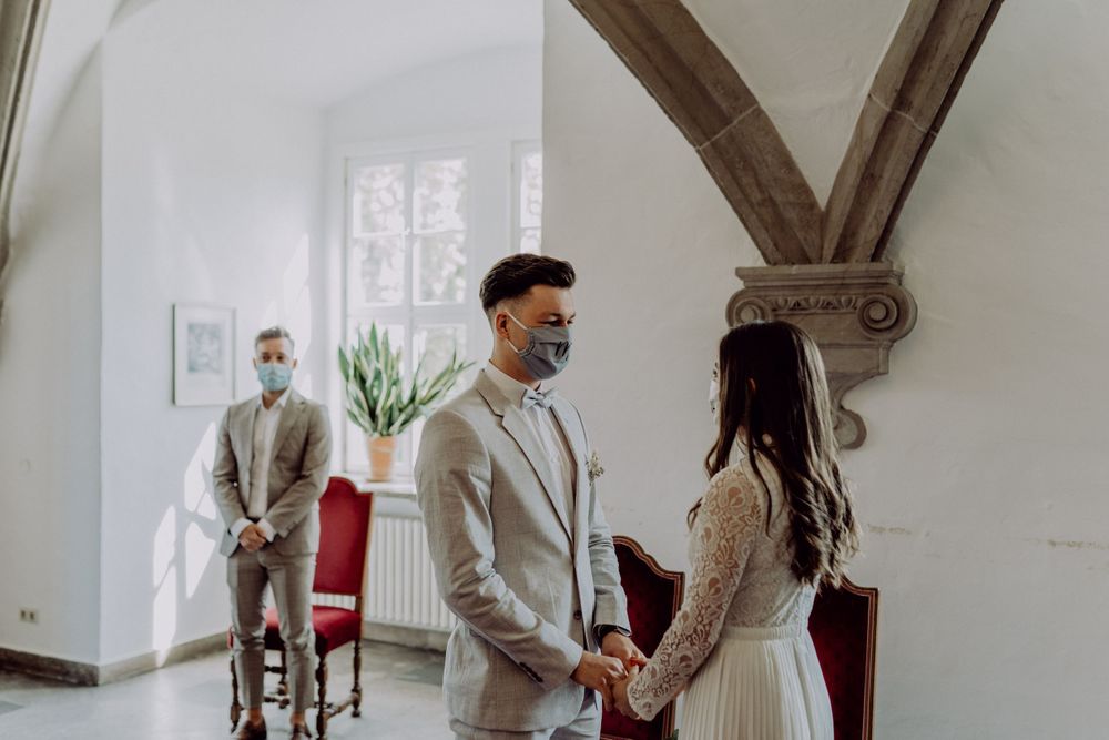 Intimate wedding moment in light-filled room with arched ceiling and wooden beams.