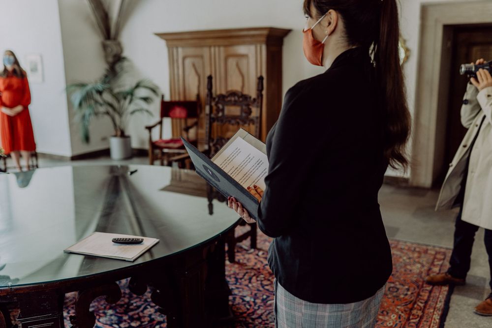 Someone reading from a document beside a glass table in historic interior.