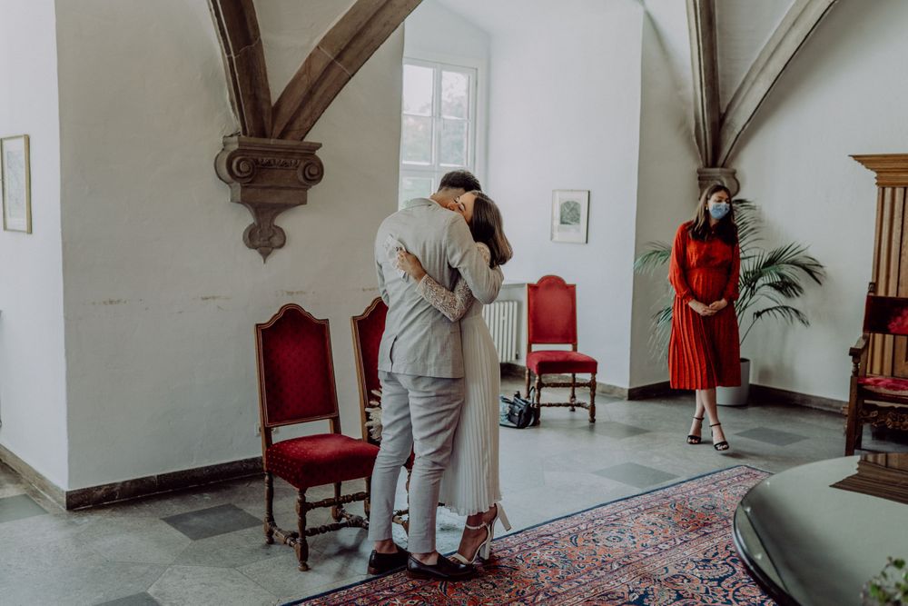 A couple shares an intimate moment in an elegant room with vintage furniture and architectural details.