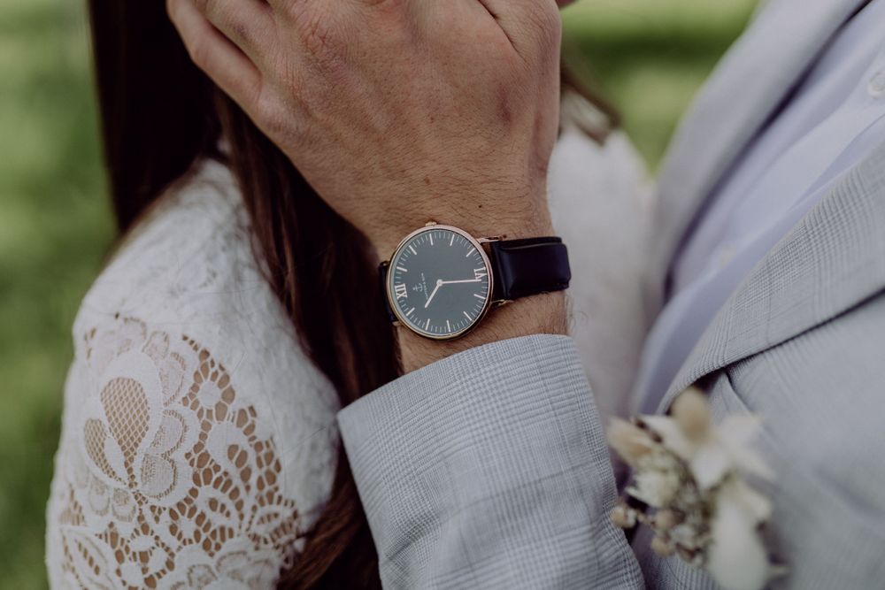 Detail shot of an elegant watch with leather strap against formal wedding attire.