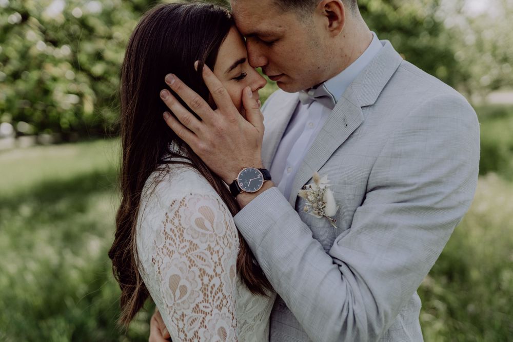 Intimate moment between couple in wedding attire sharing a tender embrace in a spring garden.