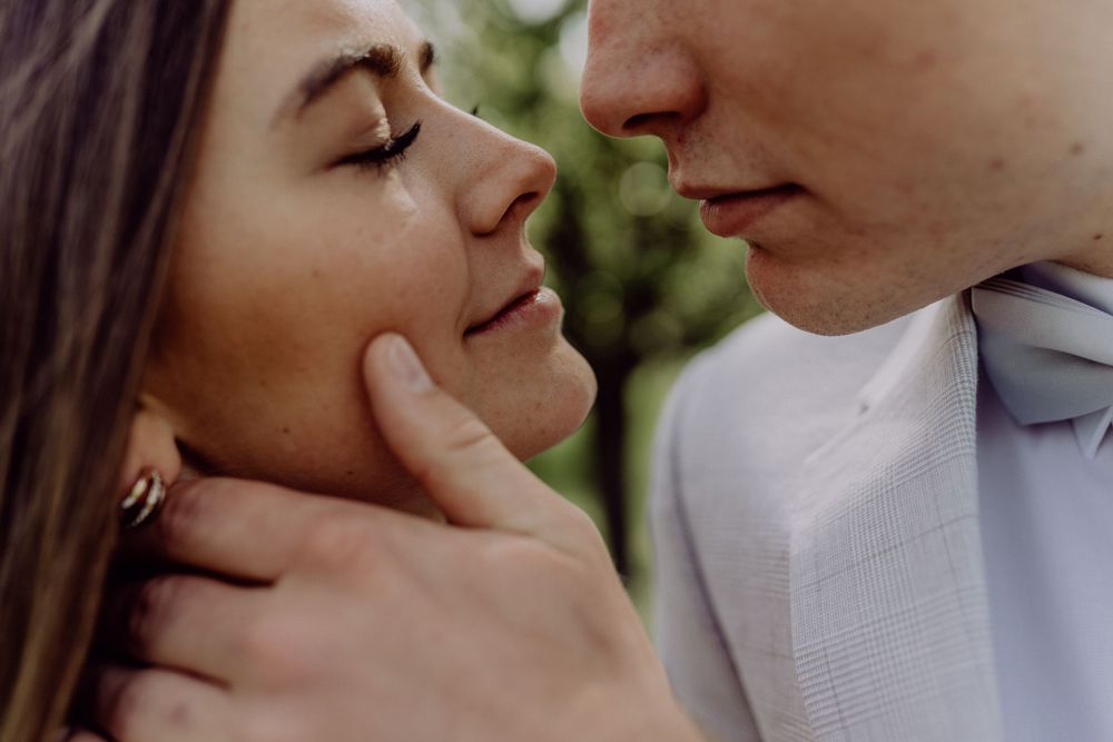 Artistic close-up portrait capturing an intimate moment between couple against blurred foliage.