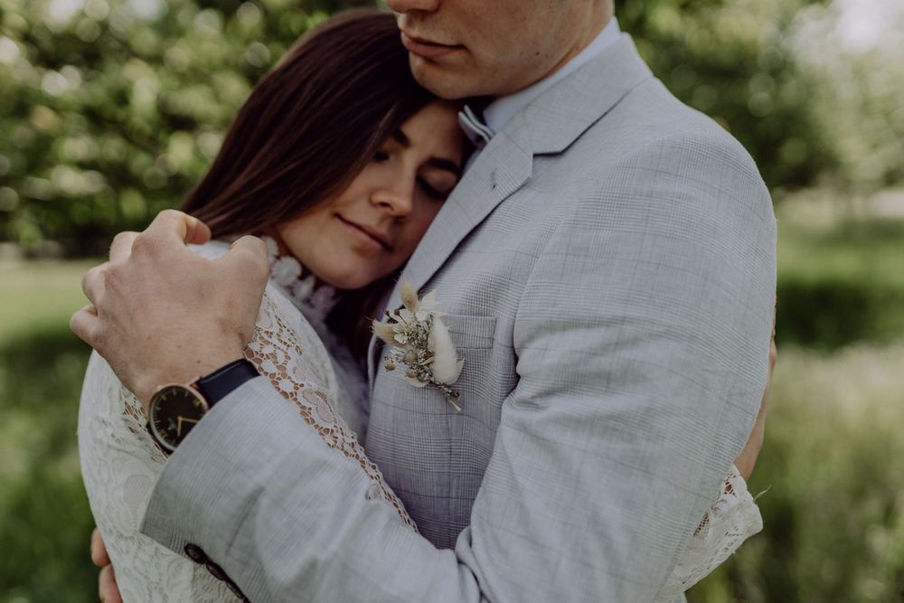 Emotional wedding portrait showing intimate embrace against soft green background.