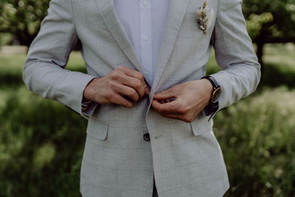 Detail shot of a light gray suit jacket with boutonniere.