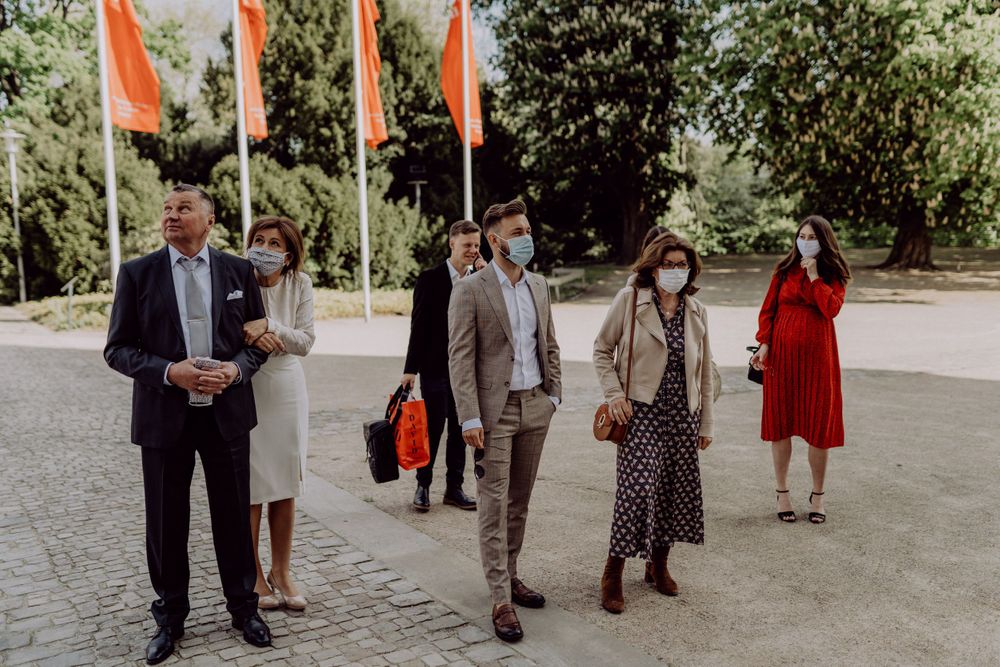 Small group of wedding guests standing near orange flags outside a building.