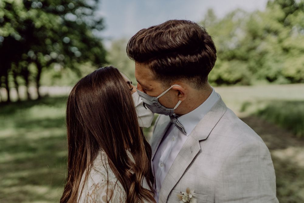 Intimate moment between couple wearing protective masks during an outdoor wedding.