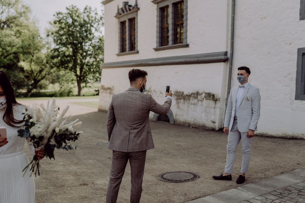 Two people in formal attire having their photo taken in front of a historic building.