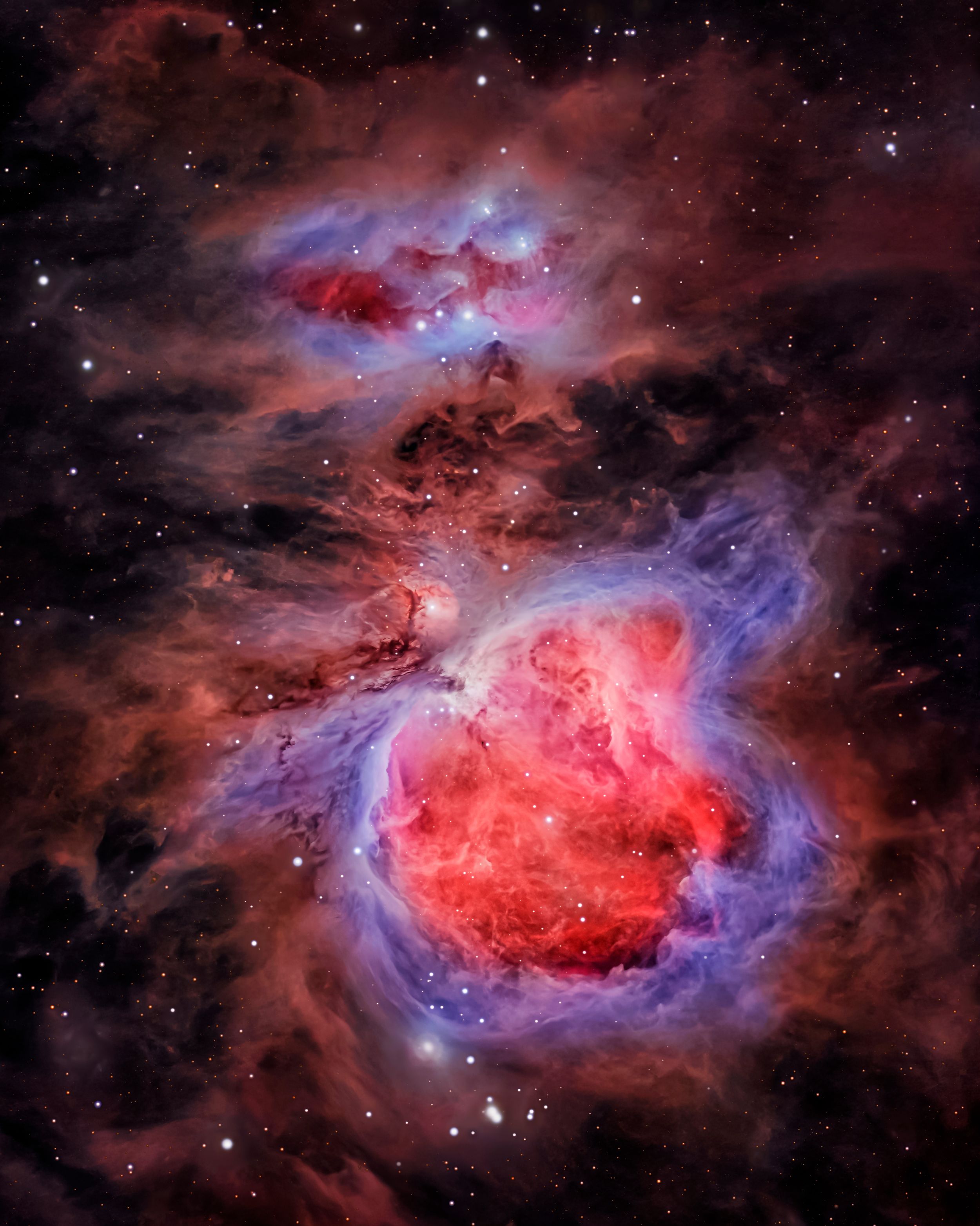 The Orion Nebula displays swirling clouds of red and blue gas illuminated by young stars.