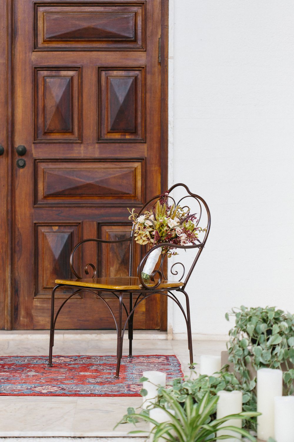 Vintage metal chair with dried flowers against wooden door entrance.