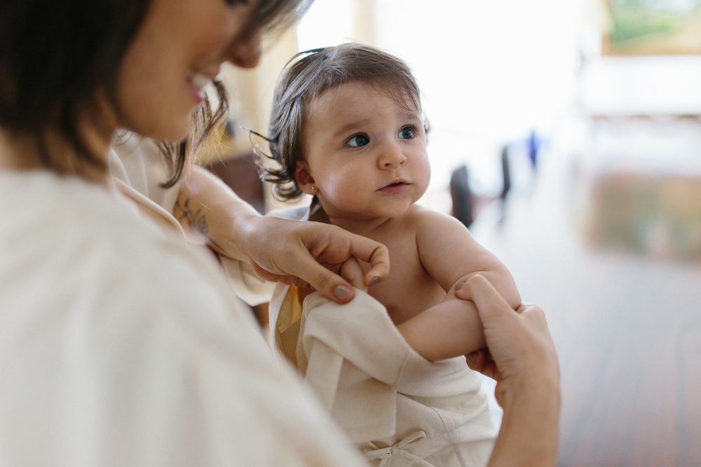 Tender moment between mother and baby in white clothing.