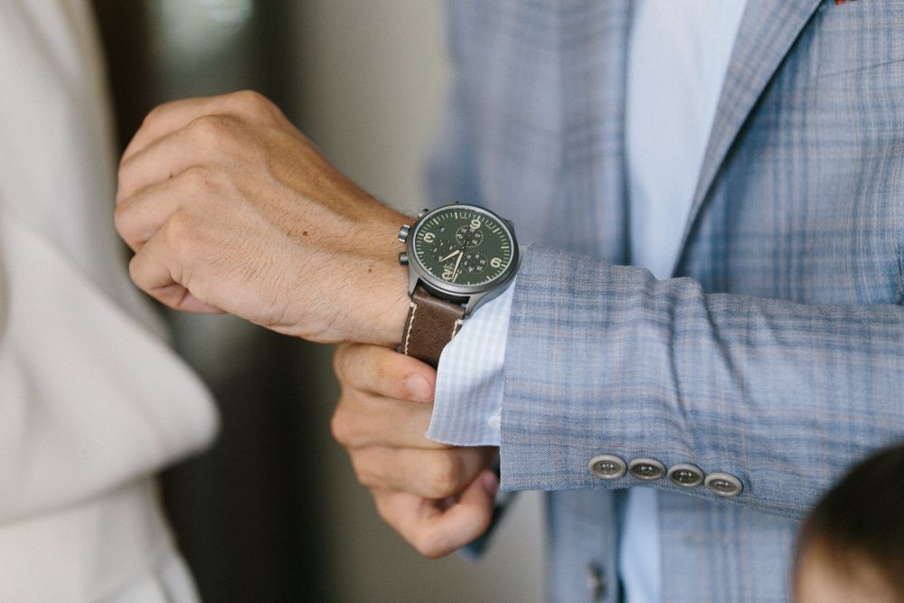 Close up of hands adjusting watch on formal attire.