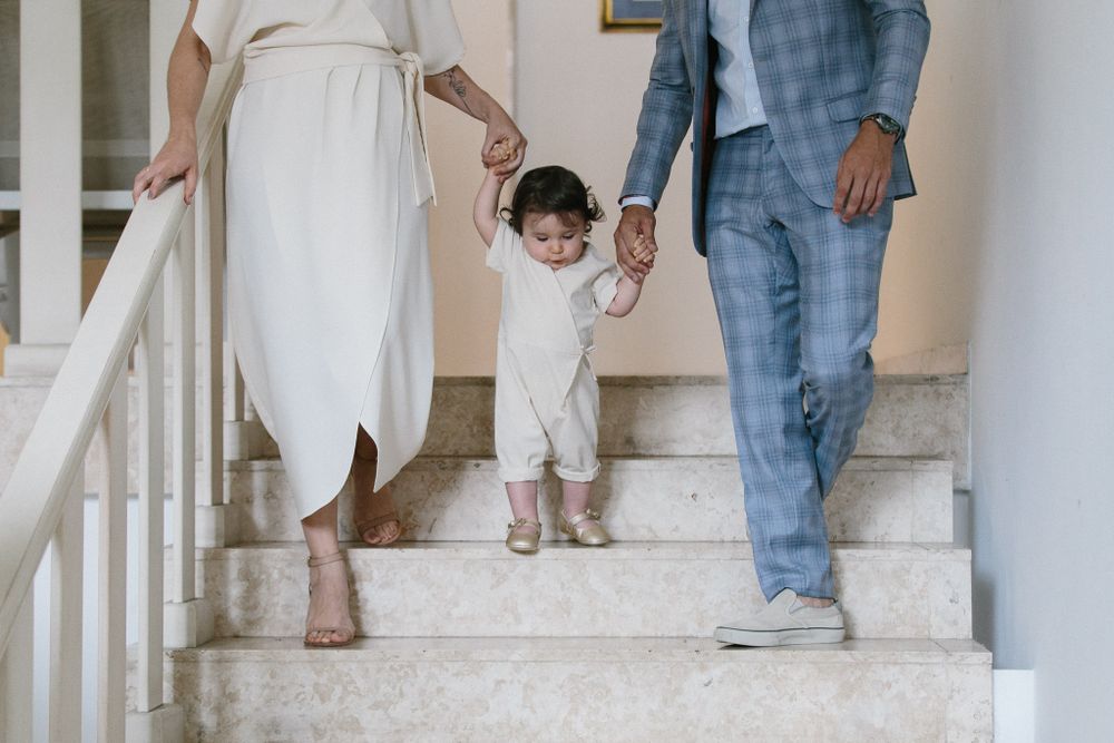 Family walking up white stairs together holding hands with toddler in middle.