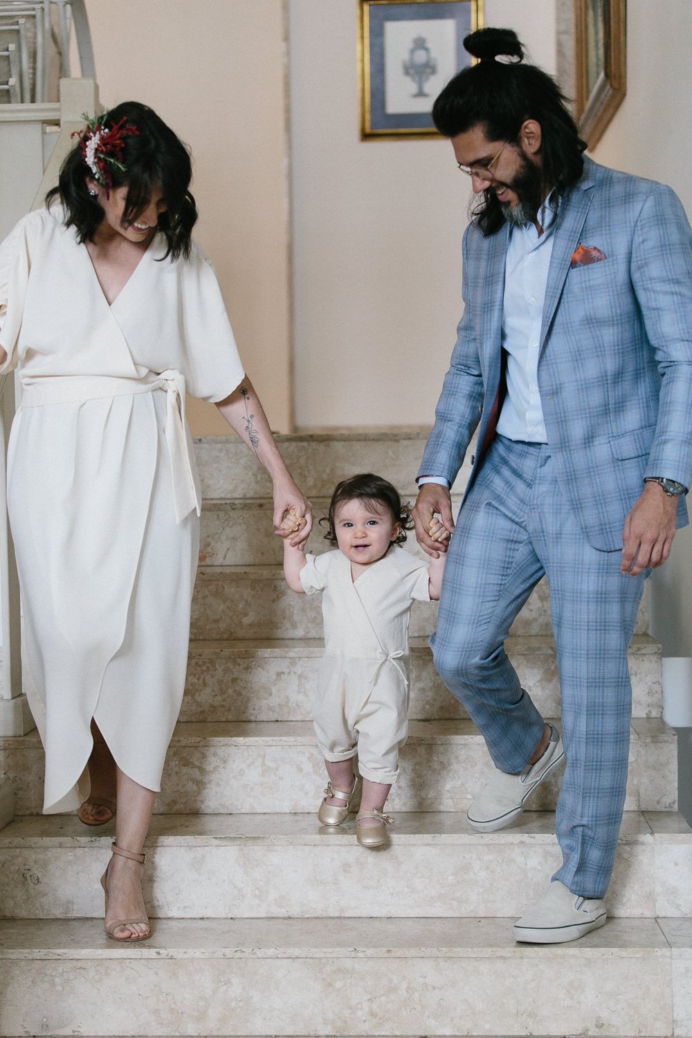 Family in coordinated formal wear walking up marble staircase together.