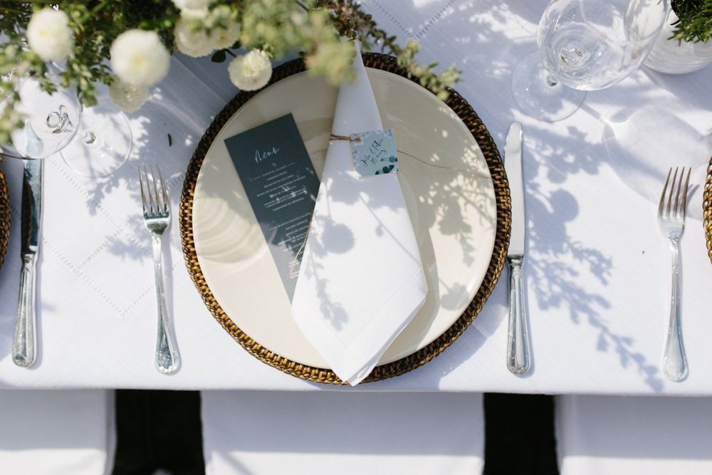 Wedding place setting with gold-rimmed charger plate and romantic floral details.
