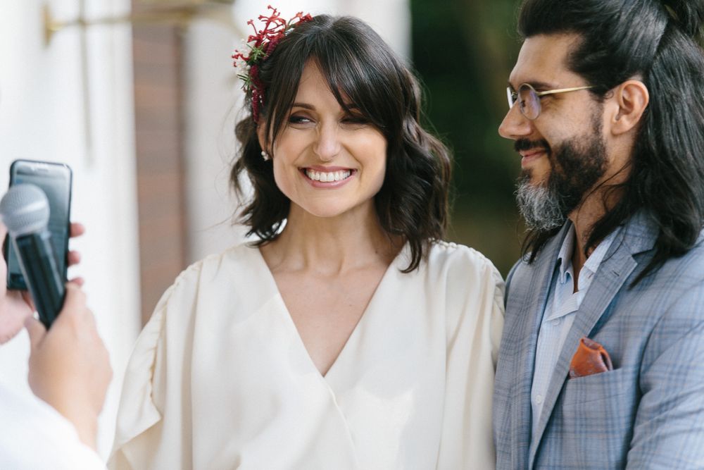 A couple shares an intimate moment while taking a selfie during a wedding ceremony.